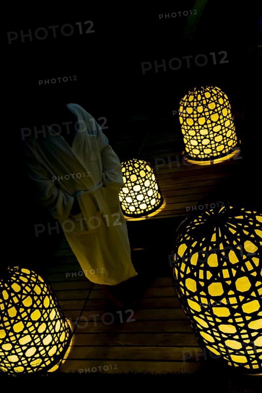 Woman with Bathrobe Standing Cloe to Illuminated Lamps at Night
