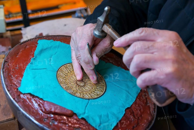 Close-up of hands engraving a detailed pattern on a metal plate in an artisanal process, Toledo, Castilla-La Mancha, Spain, Europe
