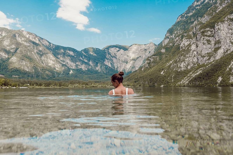 Woman standing in clear water with mountain landscape in the background, Soca Valley, Slovenia, Europe