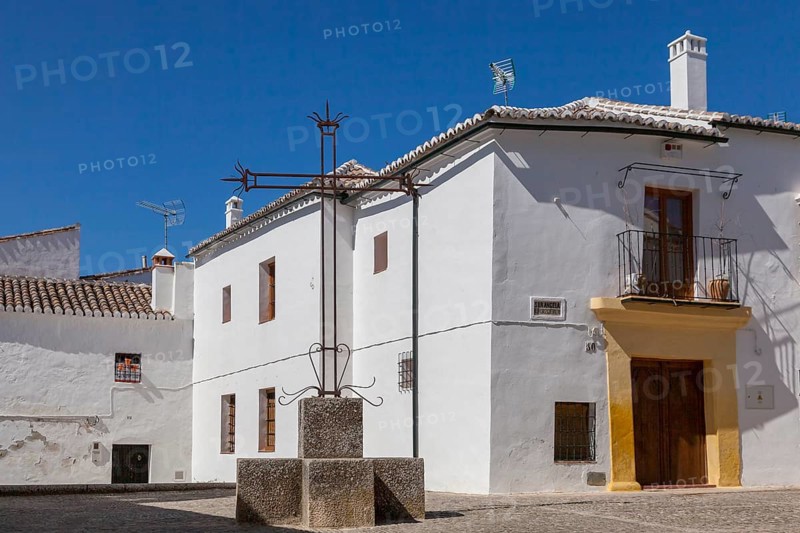 A quiet square with white houses and a central cross under a clear blue sky, Ronda, Andalusia, Spain, Europe