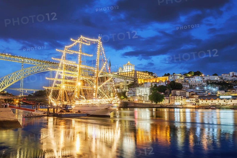 View of Vila Nova de Gaia city with a sailing ship and Dom Luis I bridge over Douro river in the evening. Porto, Portugal, Europe