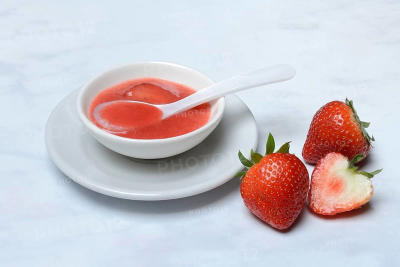 Strawberry sauce in small bowls and strawberries, strawberry coulis