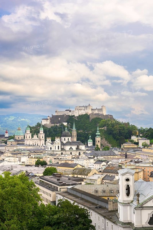 View of Salzburg with Hohensalzburg Fortress in the background and the historic city centre in the foreground, surrounded by mountains under a cloudy sky, Salzburg, Salzburger Land, Austria, Europe
