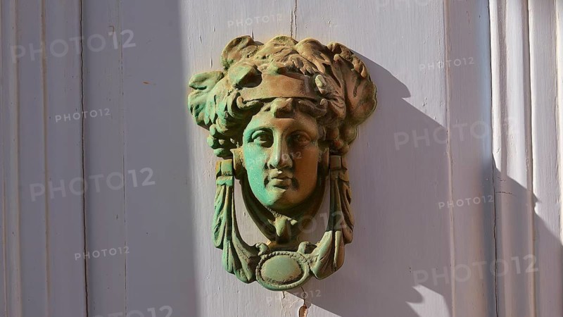 An antique bronze door knocker in the shape of a head, decorative and classically designed, Chora, main town of Patmos, Patmos, Old Town, Dodecanese, Greek Islands, Greece, Europe