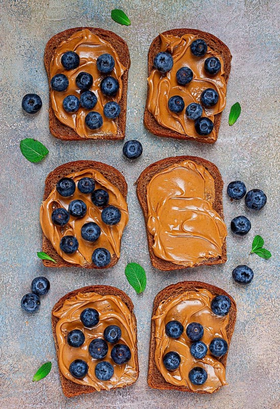 Rye bread with peanut paste and fresh blueberries, top view, no people