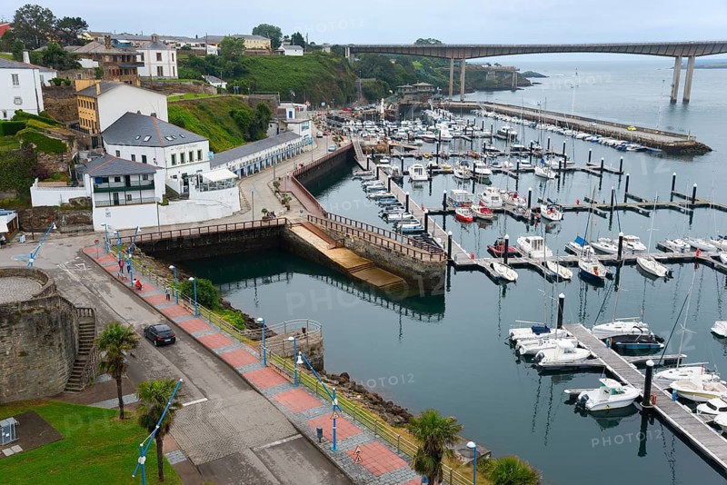 View of a harbour with numerous boats, surrounding architecture and a bridge in the background on a cloudy day, Ribadeo, River Eo, Galicia, Spain, Europe