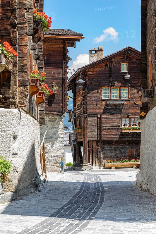 Paved footpath surrounded by old wooden houses, flower boxes and balconies and windows, historic village centre, Grimentz, Val d'Anniviers, Valais Alps, Canton Valais, Switzerland, Europe