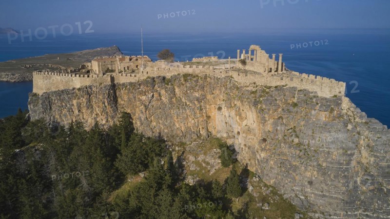 Drone shot, Acropolis of Lindos, Late afternoon light, Ancient fortress high on a cliff surrounded by pine trees and sea in the background, Archaeological site, Lindos, Rhodes, Dodecanese, Greek Islands, Greece, Europe
