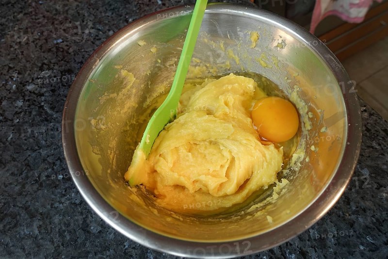 Swabian cuisine, preparing choux pastry for mini cream puffs, adding egg to raw choux pastry, cooking spoon, stirring spoon, stirring in pot, eclairs, profiteroles, shortbread, oven cakes, choux pastry doughnuts, making pastry, hearty, salty, vegetarian, baking, out of the oven, typical Swabian reinterpreted, party pastry, finger food, snacks for on the go, traditional cuisine reinterpreted, food photography, studio, Germany, Europe