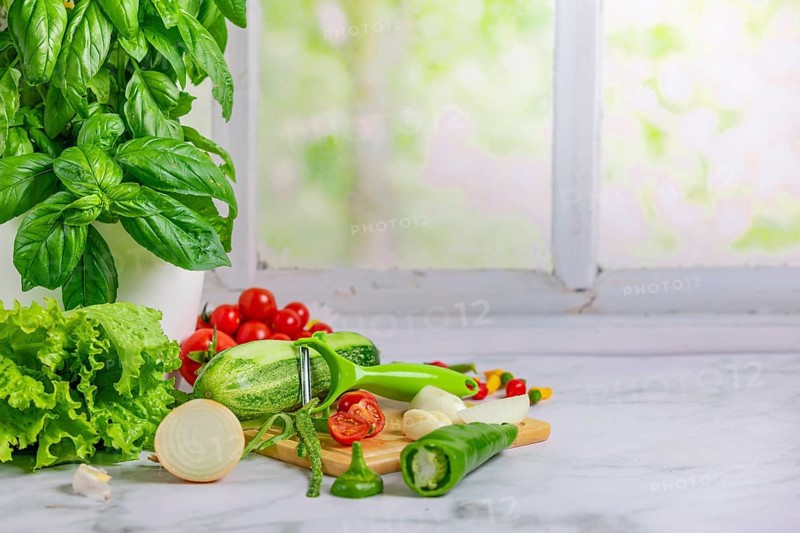 Fresh vegetables on a board, salad ingredients, cucumber, tomatoes, lettuce, basil, pepperoni, onion, garlic, peppers, partly cut open