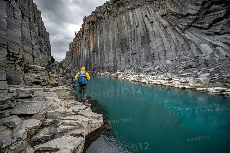 Tourist standing by the river in Stuðlagil Canyon, turquoise blue river between basalt columns, Egilsstadir, Iceland, Europe