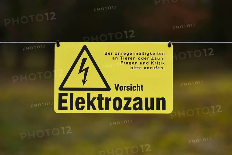 Leimen, Germany, April 2020: Yellow electric fence warning sign with German text saying 'Attention, electric fence', Europe