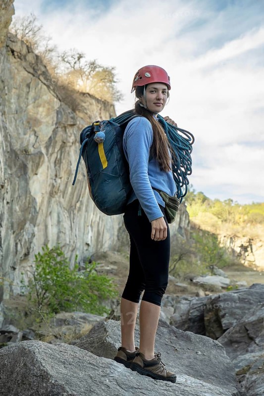 Portrait of female climber looking at camera at foot of rocky mountain. Extreme outdoor sport