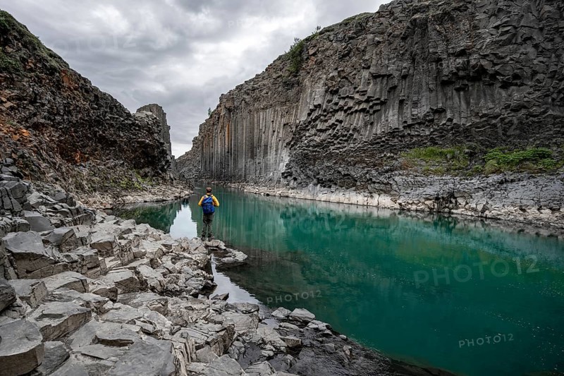 Tourist standing by the river in Stuðlagil Canyon, turquoise blue river between basalt columns, Egilsstadir, Iceland, Europe