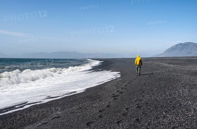 Tourist walking on a long black sand beach, Reynisfjara Beach, South Iceland, Iceland, Europe