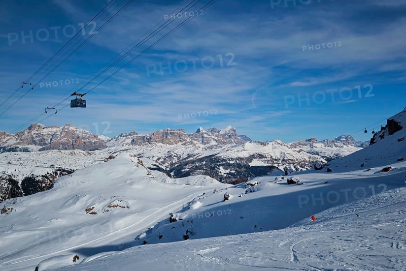 View of a ski resort piste with people skiing in Dolomites in Italy with cable car ski lift. Ski area Arabba. Arabba, Italy, Europe
