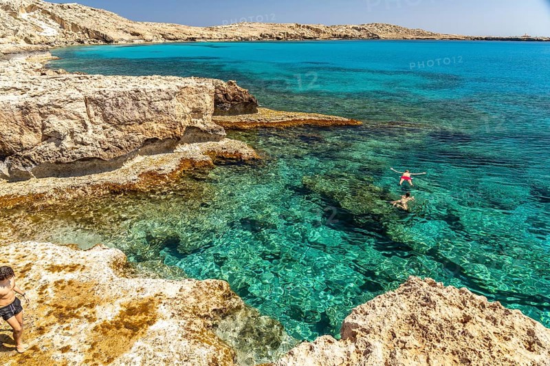 Tourists bathing in the crystal-clear turquoise waters of the Cape Greco peninsula, Agia Napa, Cyprus, Europe