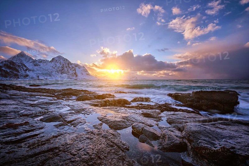 Beach of Norwegian sea on rocky coast in fjord on sunset in winter. Vareid beach, Lofoten islands, Norway, Europe