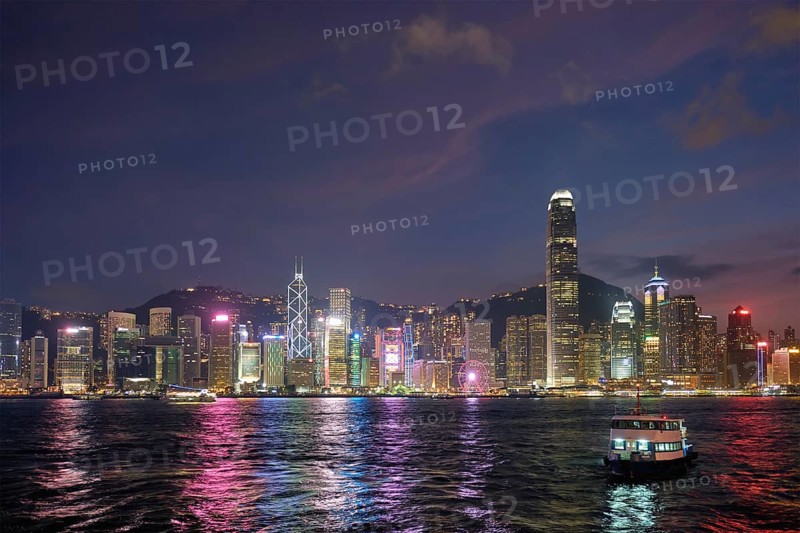 Hong Kong skyline cityscape downtown skyscrapers over Victoria Harbour in the evening illuminated with tourist boat ferries, Hong Kong, China, Asia