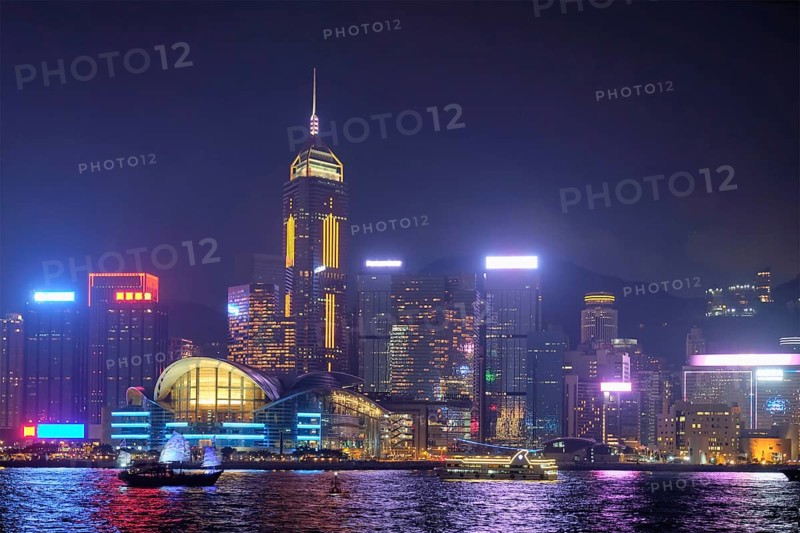 Hong Kong skyline cityscape downtown skyscrapers over Victoria Harbour in the evening illuminated with tourist boat ferries. Hong Kong, China, Asia