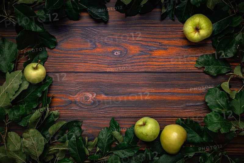 Frame of apple tree leaves and apples on wood, copying room