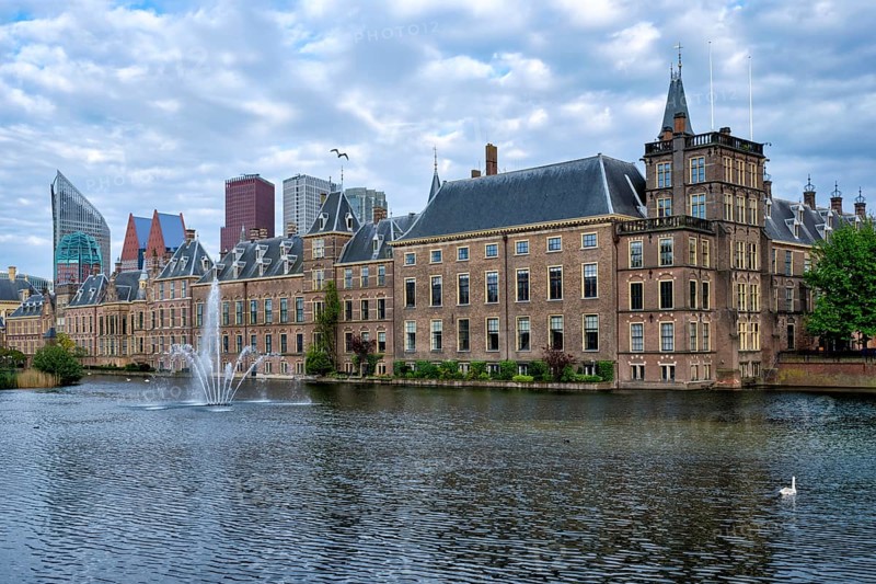 View of the Binnenhof House of Parliament and the Hofvijver lake with downtown skyscrapers in background. The Hague, Netherlands