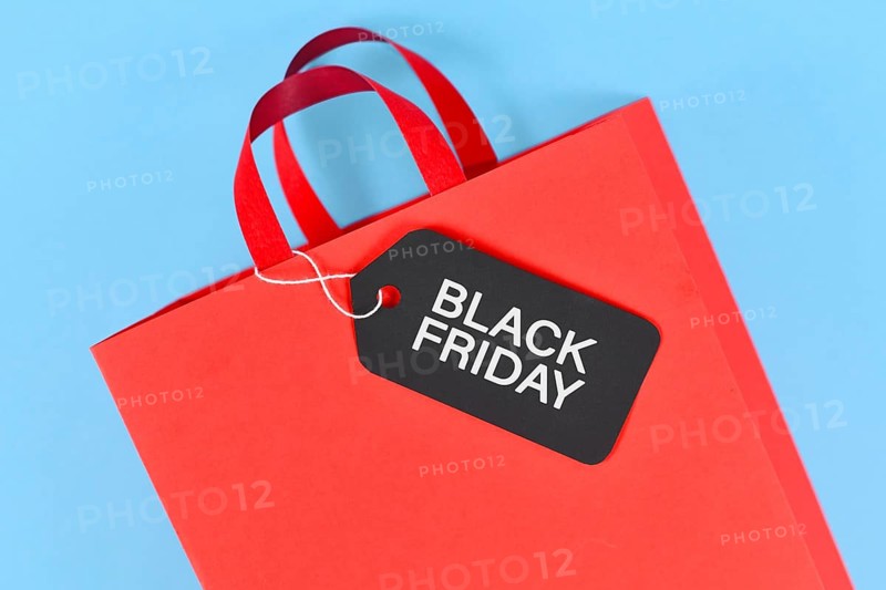 Black Friday sale label on red paper shopping bag on blue background