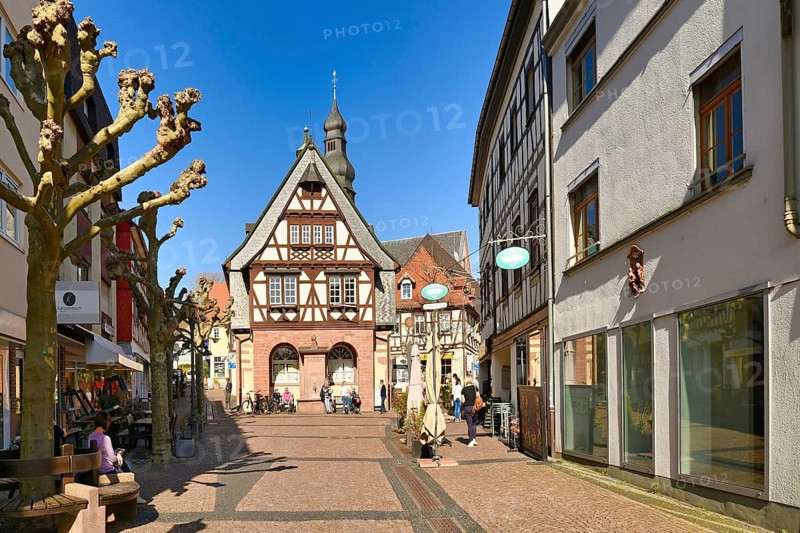Hofheim, Germany, March 2021: Street with traditional half timbered buildings in old historic city center of Hofheim full of people on sunny day, Europe