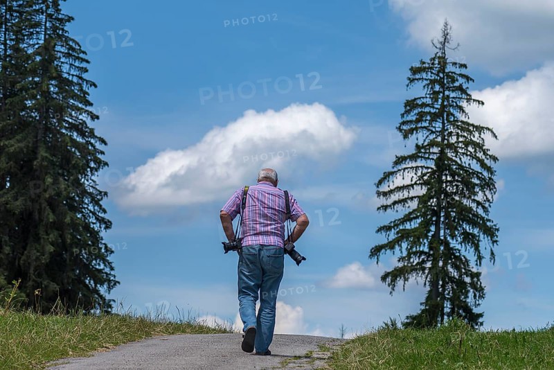 Photographer with equipment looking for motifs in the mountains, Eisenberg (Ostallgäu), Bavaria, Germany, Europe