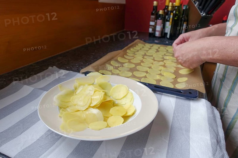 Preparation of cress soup with crisps, potato wheels on baking tray, plate, Swabian cuisine, hearty soup, vegetarian, healthy, salty, typical Swabian reinterpreted, traditional cuisine, food photography, studio, men's hands, tea towel, Germany, Europe