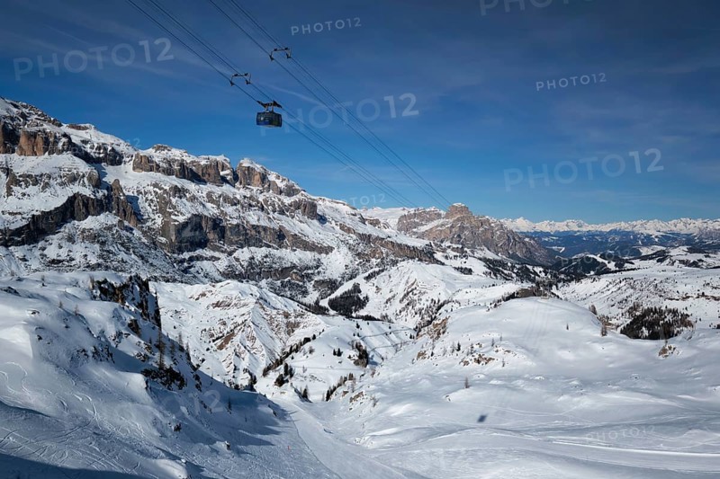 View of a ski resort piste with people skiing in Dolomites in Italy with cable car ski lift. Ski area Arabba. Arabba, Italy, Europe