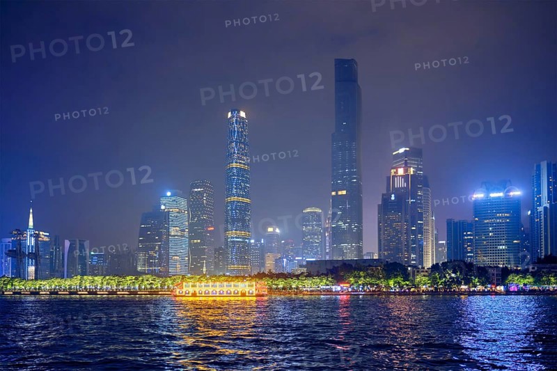 Guangzhou cityscape skyline over the Pearl River with tourist boat illuminated in the evening. Guangzhou, China, Asia