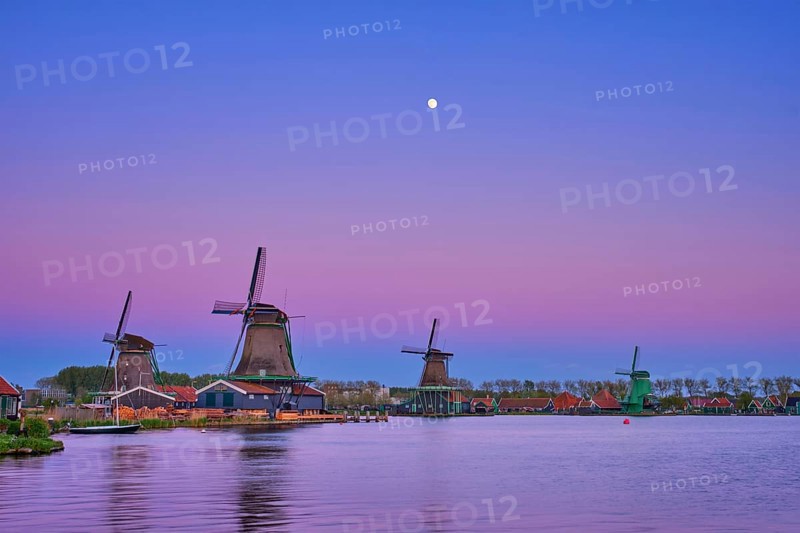 Windmills at famous tourist site Zaanse Schans in Holland in twilight on sunset with moon. Zaandam, Netherlands
