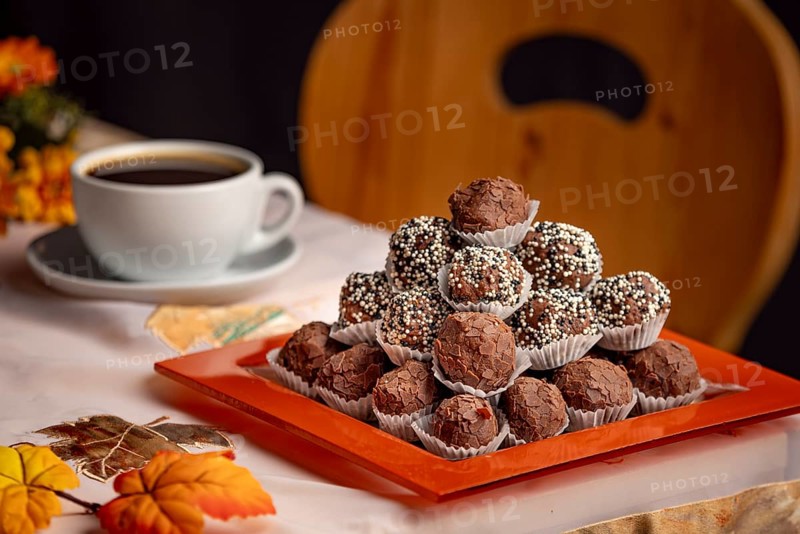 A plate of rum balls on a table with autumnal decorations and a cup of coffee