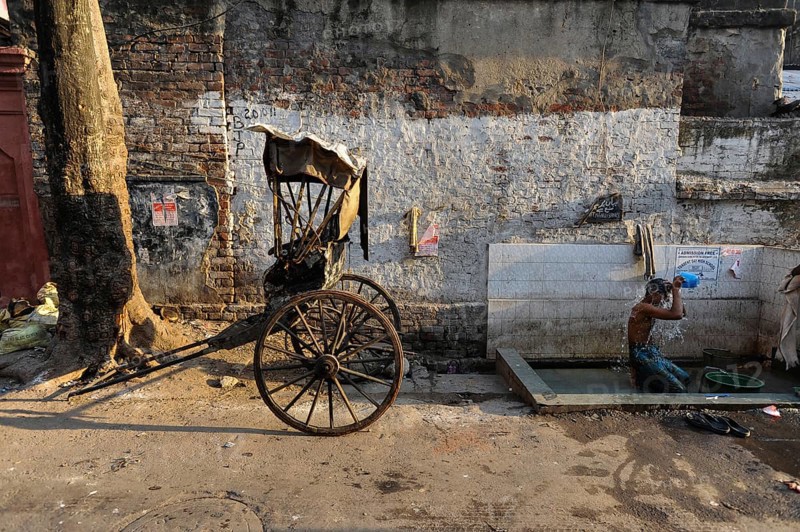 24.02.2011, Kolkata, West Bengal, India, Asia, A rickshaw driver washes himself next to his wooden rickshaw on a roadside in Kolkata, the only city in India where hand-pulled rickshaws still exist, Asia