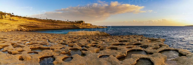 A panorama landscape view of the tidal pools and cliffs at Il-Hofra z-Zghira Bay in Malta