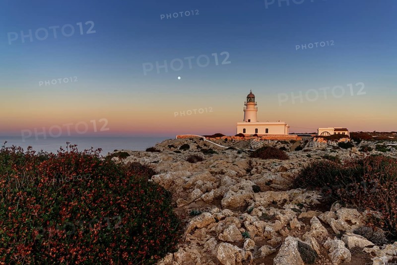 A view of the Cap de Cavalleria Lighthouse on Menorca at sunset with a full moon rising
