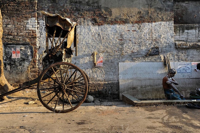 24.02.2011, Kolkata, West Bengal, India, Asia, A rickshaw driver washes himself next to his wooden rickshaw on a roadside in Kolkata, the only city in India where hand-pulled rickshaws still exist, Asia