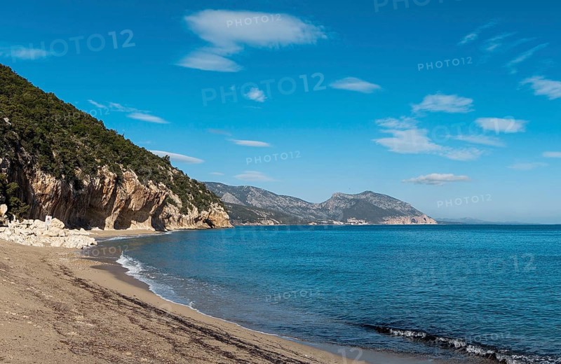 The overhanging cliffs and sandy beach at Cala Luna on the east coast of Sardinia