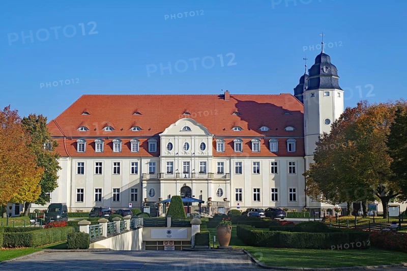 Large castle with a red roof against a blue sky, surrounded by autumn trees, Malchower See, Schlosshotel, Fleesensee, Mecklenburg-Vorpommern, Germany, Europe