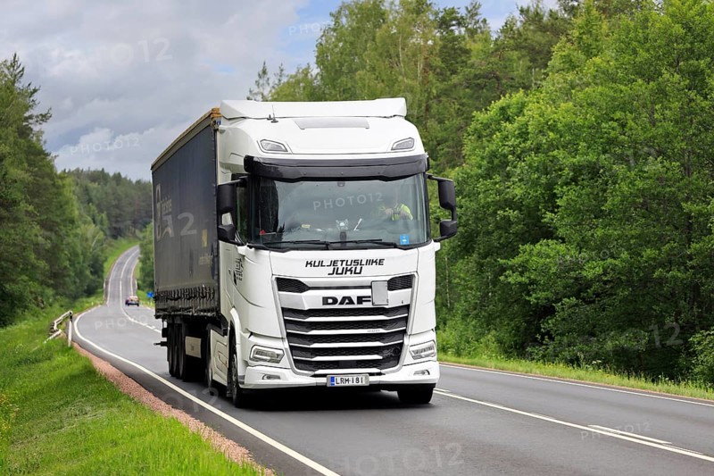 White DAF XG 480 truck pulls curtainside semi trailer uphill along highway 52 on a day of summer. Salo, Finland. June 19, 2024