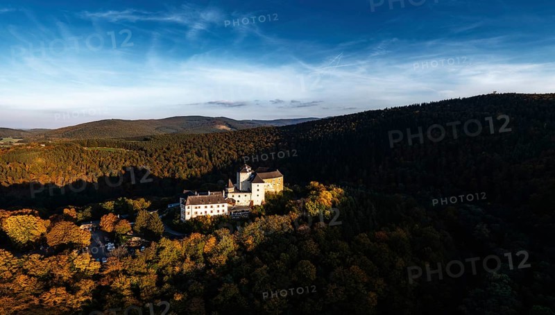Lockenhaus, Austria, 7 October, 2022: panorama of Lockenhaus Castle surrounded by autumn forest in warm evening light, Europe
