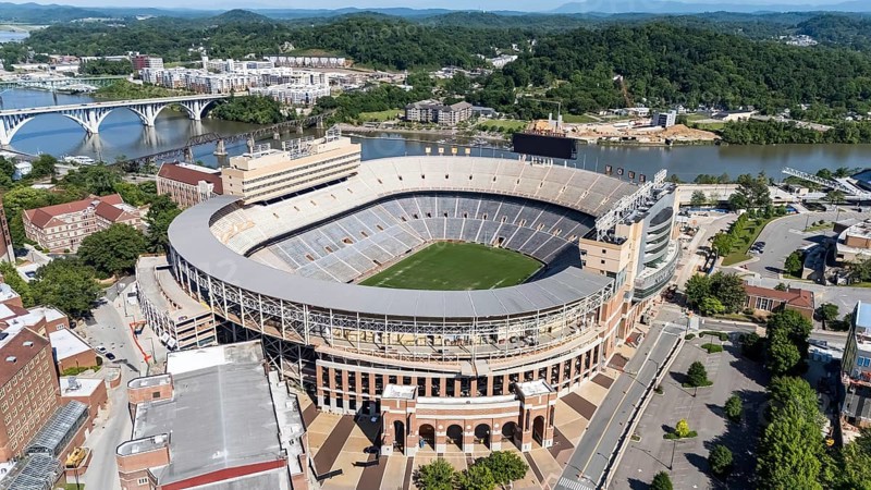 An aerial view of Neyland Stadium reveals a massive, iconic structure nestled by the Tennessee River, with its distinctive bowl shape and seating for over 100, 000 fans, showcasing its rich football heritage