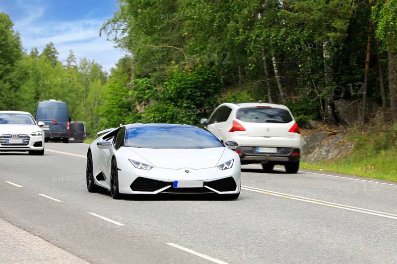 White Lamborghini Huracán AWD 2015 sports car at speed in highway traffic on a day of summer. Salo, Finland. June 20, 2024