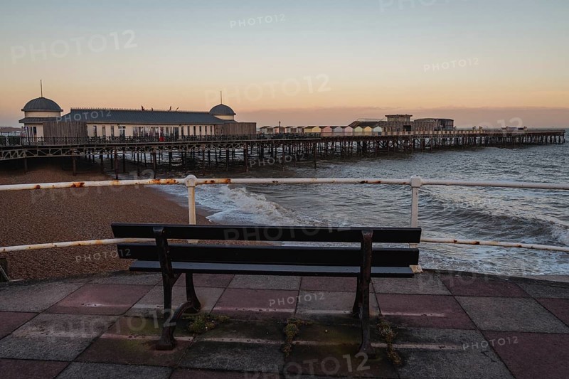 Hastings, East Sussex, England, UK, May 11, 2022: Evening mood on the beach, with a bench overlooking the the pier