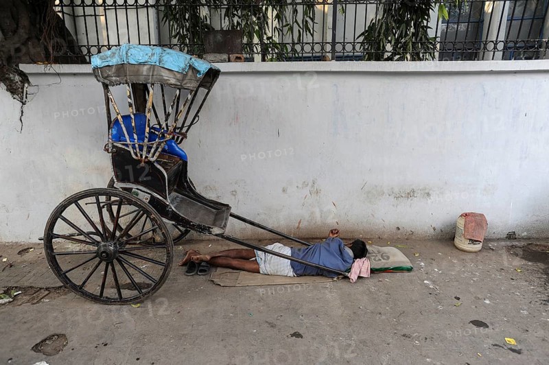 25.02.2011, Kolkata, West Bengal, India, Asia, A rickshaw driver sleeps next to his wooden rickshaw on a roadside in Kolkata, the only city in India where hand-pulled rickshaws still exist, Asia