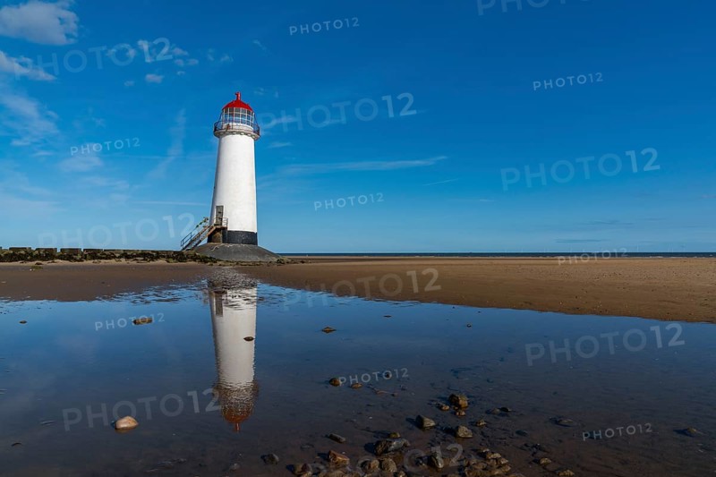 A view of the Point of Ayr Lighthouse and Talacre Beach in northern Wales with reflections in a tidal pool