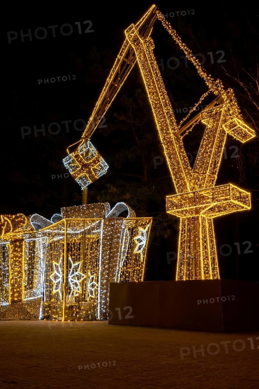 Construction crane symbol of Shipyard Holiday illuminated decorations in Gdansk Poland. Beautiful Christmas fair at night. Advent winter time in Europe background. Christmas Markets in December Ornamented for celebration