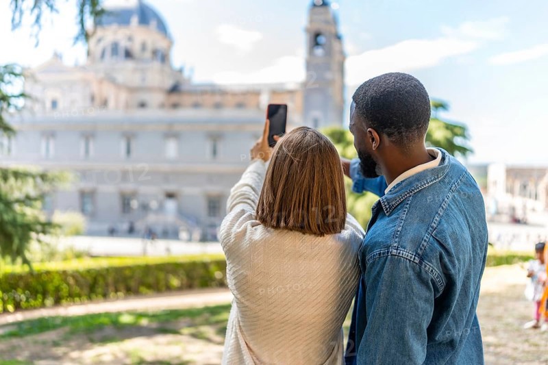Rear view of a multi-ethnic couple taking a photo of a monument visiting a city