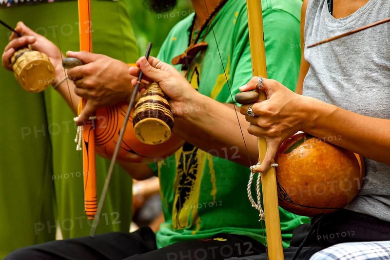 Musicians playing an Afro Brazilian percussion musical instrument called a berimbau during a capoeira performance in the streets of Brazil